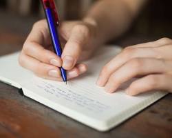 صورة person writing down goals in a notebook