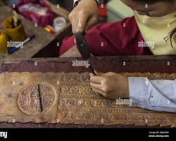 An artisan carefully carving a piece of wood at the Artisans Angkor workshop.