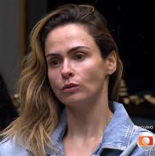 Fernanda Paes Leme em close-up, com cabelo loiro ondulado e vestindo jaqueta jeans. Ela olha para o lado com expressão séria.