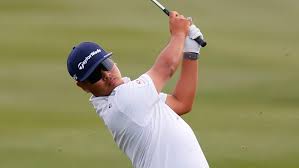 Male golfer in white shirt completing a swing