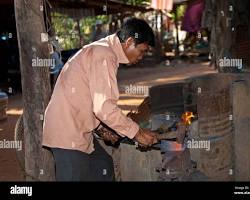 Cambodian blacksmith forging red-hot iron in a traditional workshop.