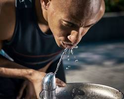 person drinking water from a water fountain
