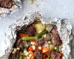 Изображение: Meat and vegetables wrapped in aluminum foil and cooking on a grill