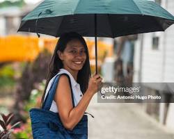 Image of someone smiling while holding an umbrella in the rain in Houston