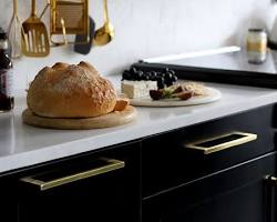 Image of kitchen with gold cabinets, marble countertops, and black appliances