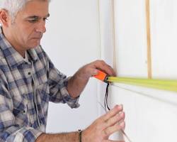 Image of homeowner measuring a wall with a tape measure