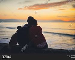 Image of two people embracing on a beach with a beautiful sunset in the background