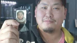 Taiwanese-born Conny Wiik, who was adopted by a Finnish family when he was a year old, holds up a photograph of himself as a baby on Saturday. - p02-140304-p1r