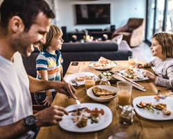 happy family having lunch in a cafe with a child playing in a kids' spaceの画像