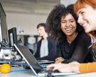 business consultant sitting at a desk with a client, giving them advice while laughing.