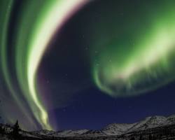 Image of Northern Lights shimmering over snowcapped Alaskan mountains