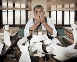 Image of someone holding their head in their hands, surrounded by bills