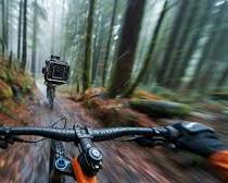 Image of person mountain biking through a scenic forest trail, wearing an action camera on their helmet to capture the exhilarating ride.