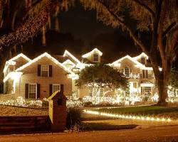 House illuminated with festive Christmas lights, showcasing a beautifully decorated exterior with twinkling rooflines and surrounding landscaping, reflecting the professional installation services of Christmas Lights by Amco.