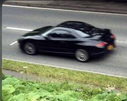 Image of person driving a car with a speed camera flash in the background