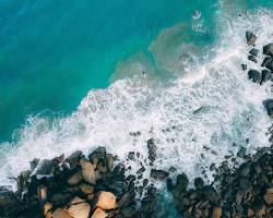 Image of blue ocean with waves crashing on a rocky shore