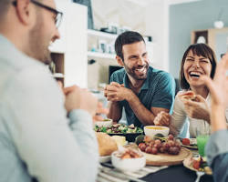 family enjoying a meal together, smiling and laughingの画像