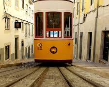 Image of Lisbon, Portugal with colorful buildings, a historic tram, and a castle on a hill.