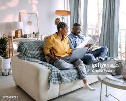 Image of someone relaxing on a couch with a laptop, surrounded by paperwork