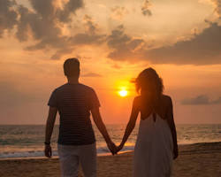 couple holding hands and walking along the beach at sunset in Fukuoka.の画像