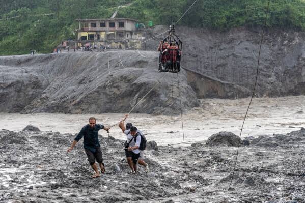 Nepal flood survivors trade food for medicine and cross rivers by zip line as rescue efforts continue for 900 missing tunnel workers