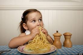 Bambina sta mangiando un piatto di spaghetti più grande di lei