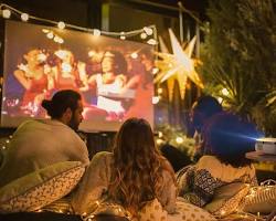 Изображение: family enjoying a movie night in their smart home, with the lights dimmed and the entertainment system controlled by voice commands.