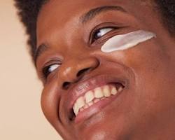 Image of Black woman applying castor oil to her face