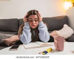 Image of someone looking stressed sitting on a couch with a pile of paperwork