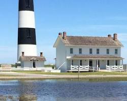 Image of Outer Banks' shoreline with colorful beach houses and a historic lighthouse