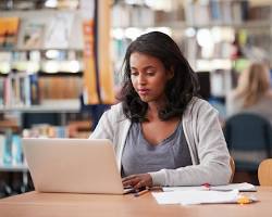 student working on a laptop in a library resmi