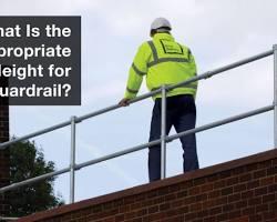 Image of construction worker using a guardrail for safety on a high platform