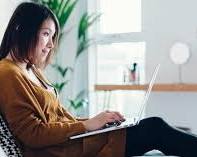 Image of someone relaxing on a couch with a laptop, surrounded by job search materials