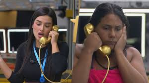 Duas mulheres conversam ao telefone em um reality show, com expressões de surpresa e preocupação.