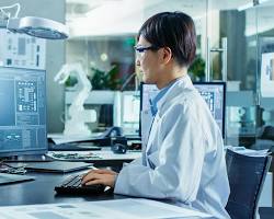 Image of person working on a computer, surrounded by documents and files, with a focus on a screen displaying electronic tender information