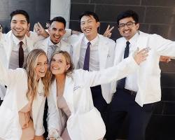 Image of group of medical students in white coats, smiling and laughing