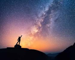 Image of person reaching for a star amidst a starry night sky