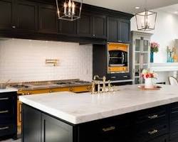 Image of kitchen with black cabinets, marble countertops, and gold hardware
