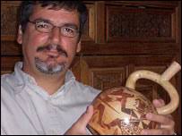 Archaeologist Luis Jaime Castillo (BBC). Archaeologist Luis Jaime Castillo holds a Moche ceramic depicting warriors engaged in ritual combat - _40881159_pot_bbc_203