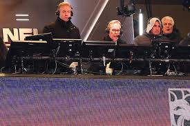 Troy Aikman and Joe Buck sitting in a broadcast booth during an NFL game.