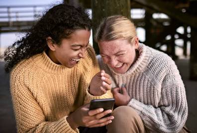 Dos personas riendo y divirtiéndose mientras se escriben mensajes, demostrando una conversación interesante y animada en el chat de citas.