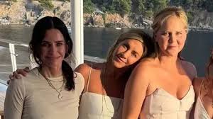 Jennifer Aniston, Amy Schumer, and Courteney Cox posing together on a yacht