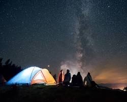 Image of family camping under a starry night sky.