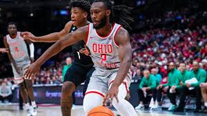 Basketball player in white Ohio jersey dribbling past defender