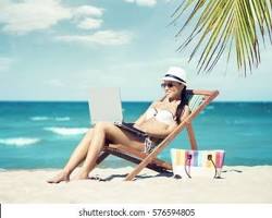 Image of nurse relaxing on a beach with a laptop and a cup of coffee