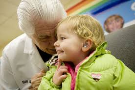 Bill Austin, founder of the Starkey Hearing Foundation, fits Savannah Andersen, 3, with digital hearing aids Tuesday at Washington School for the Deaf. - 20101130-204419-pic-133774406