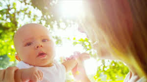 Smiling Blonde Baby Girl Close Up Held In Loving Mothers Arms In Sunshine At Park Shot ... - stock-footage-loving-young-caucasian-mother-holding-up-happy-baby-son-in-sunshine-outdoors-sun-lens-flare-shot-on