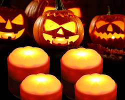 Image of jacko'lantern carved from a pumpkin, with a candle flickering inside.