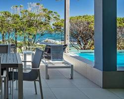 luxury apartment terrace furnished with table and chairs facing a residential pool and the sea, généré par IA