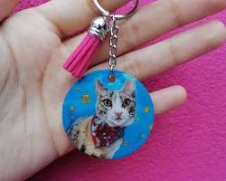 person holding a keychain with their pet's portraitの画像